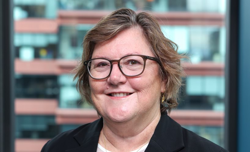 Profile photo of woman with short hair and glasses smiling at camera.
