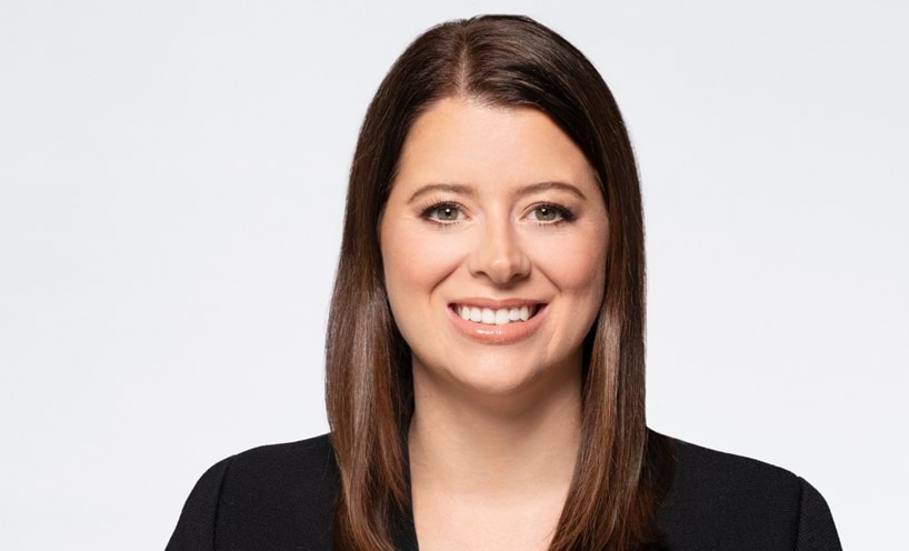 Carly has a side part in her long brown hair.