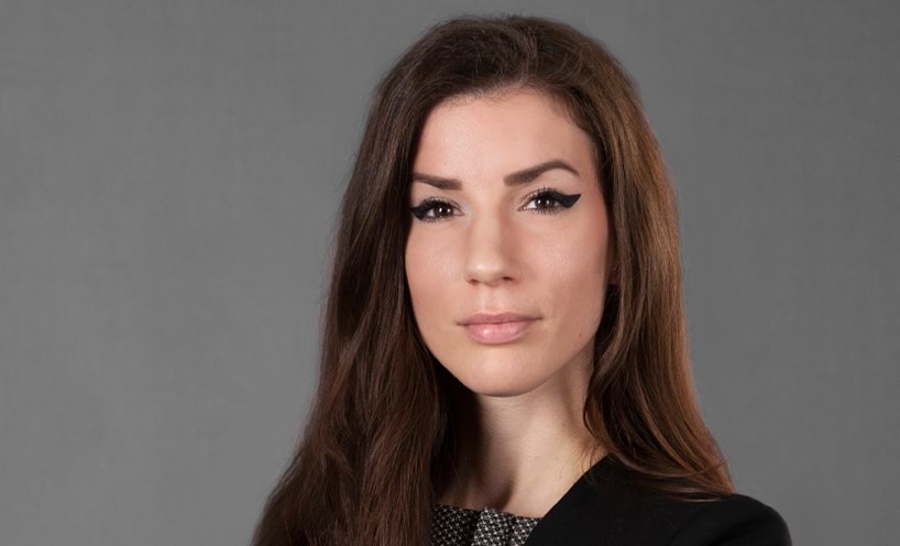 Nonni has long brown hair and is wearing a dark blazer.